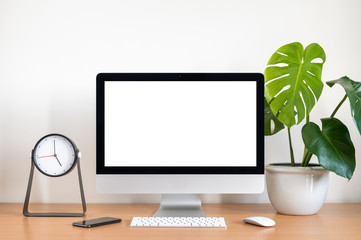 Blank screen of All in one computer, keyboard, mouse, monstera plant pot and clock  on wooden table - obrazy, fototapety, plakaty