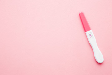 Pregnancy test with two stripes on light pastel pink table background. Positive result. Closeup....