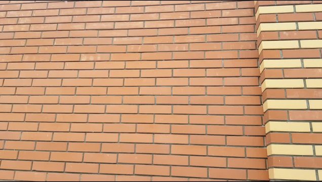 Modern red building brick wall covered in snow, snowfall in winter, 4K video