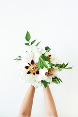 Woman hands holding white peonies flowers on white background. Flat lay, top view.
