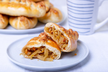 Pies (pirozhki) with cabbage. Homemade baking. Traditional Russian and Ukrainian cuisine. In the background is a dish with pies. Close-up.