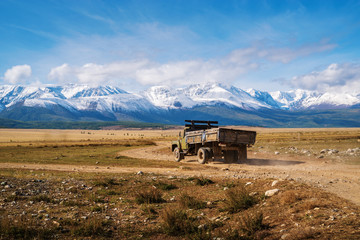 Naklejka premium Altai Republic, Russia - September, 15, 2019: ZiL-130 truck driving along a field road, the North Chuy Range on the horizon