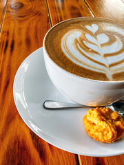Cup of cappuccino on a textural brown table with cookies, free space.