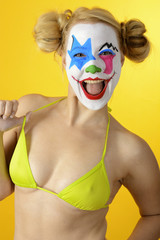 Clown disguised as a horrorclown celebrates Halloween or carnival in bikini and is silly and funny