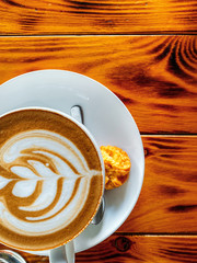 Cup of cappuccino on a textural brown table with cookies, free space.