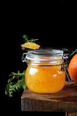 Citrus jam of kumquats and two sorts of mandarins with thyme and anise in a glass jar on the edge of the wooden table