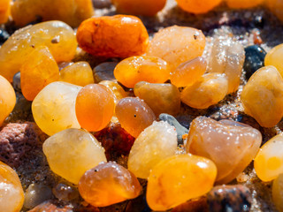 Small amber stone and pebbles on the sandy beach. Shallow wet amber washed by waves. Natural...
