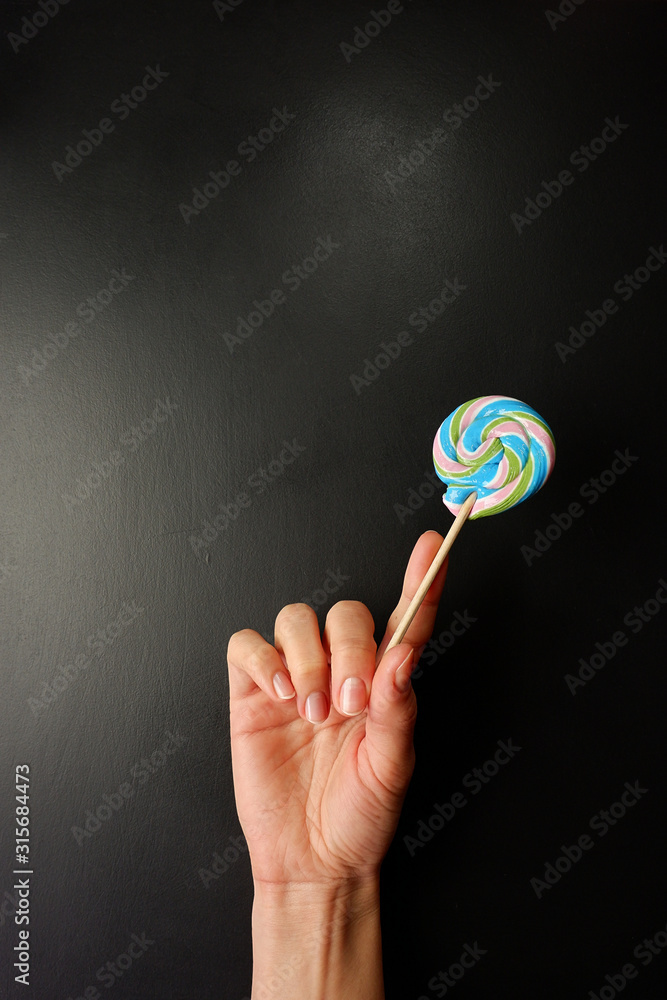 Canvas Prints Lollipop in hand on a black background, empty place for text