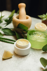 Yellow natural moisturizer in a white jar on a gray background. Cream of natural ingredients, aloe, eucalyptus, lemon and leaves. Perfect homemade natural face mask