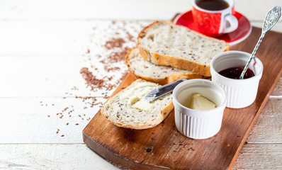 Sliced toast bread with butter on wooden cutting board. Morning breakfast with coffee, butter and toasts.