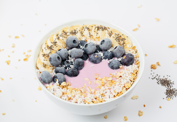 Healthy smoothie bowl with yogurt, blueberry, bananas, coconut, chia seeds and granola