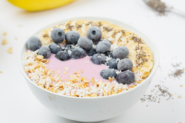 Healthy smoothie bowl with yogurt, blueberry, bananas, coconut, chia seeds and granola