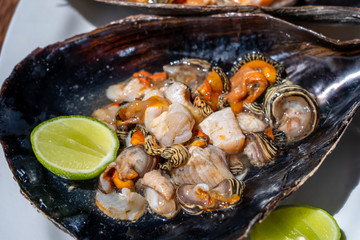 Raw clam meat in a large seashell served for food at a local restaurant on the island of Zanzibar, Tanzania, East Africa