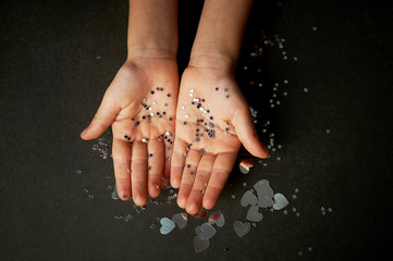 Children's hands in glitter sours of silver color. Faith in miracles.