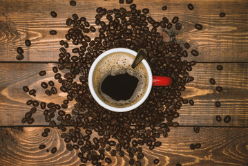 Coffee cup and beans on rustic wooden background. Top view with copyspace for your text. Coffee beans spread on the table.