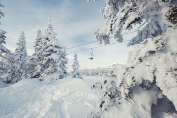 Fototapeta na wymiar ski lift behind Frozen snow cowered trees, mountains landscape in ski resort