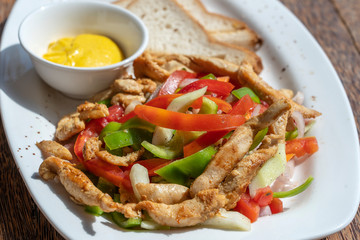 Roasted chicken fillet with vegetables and bread on a white plate, closeup