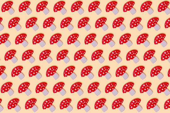 Red mushroom with white spots wooden toy in a row on yellow background
