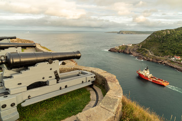 A modern deep water drilling rig support ship going out to sea under the watchful old cannon from the Queen's Battery #1, St. John's, Newfoundland