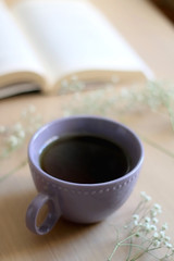 Cup of tea, book and gypsophila flowers on wooden table. Selective focus.