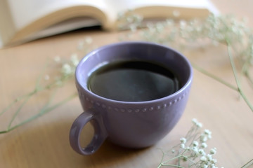 Cup of tea, book and gypsophila flowers on wooden table. Selective focus.