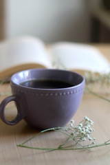 Cup of tea, book and gypsophila flowers on wooden table. Selective focus.