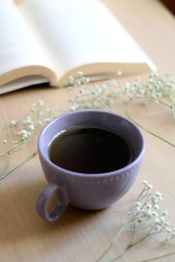 Cup of tea, book and gypsophila flowers on wooden table. Selective focus.