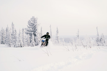 Rider with snowbike on snow covered mountain slop. Sunny fog, outdoor activity in winter day