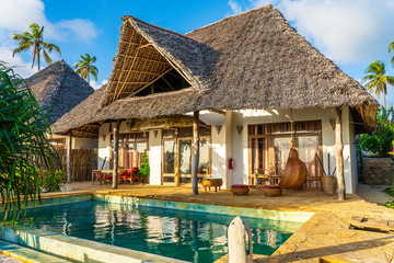 Morning view of a luxury villa on the tropical beach near sea on the island of Zanzibar, Tanzania,...