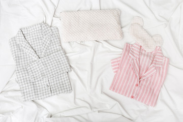 Pink and grey pajamas for men and women, and sleep mask for eye on white cotton bedsheet....