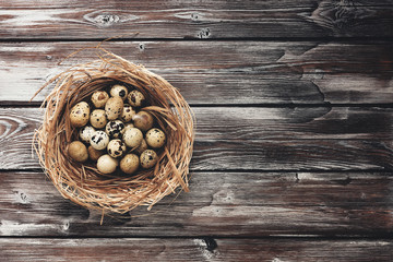 Quail eggs in a nest on a wooden board rustic background. Top view, flat lay,toned, place for text