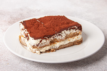 Tasty piece of tiramisu on craft background. Homemade tiramisu closeup.