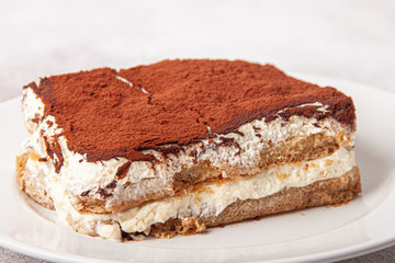 Tasty piece of tiramisu on craft background. Homemade tiramisu closeup.