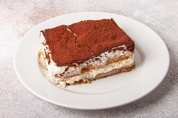 Tasty piece of tiramisu on craft background. Homemade tiramisu closeup.