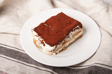 Tasty piece of tiramisu on craft background. Homemade tiramisu closeup.