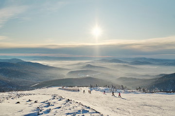 Beautiful landscape with foggy sunny mountains in ski resort view, nature and sport background, sunset skyline