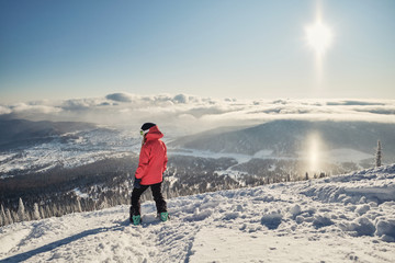 snowboarder woman on mountain slop, preparing to snowboarding. Sunny winter day in ski resort