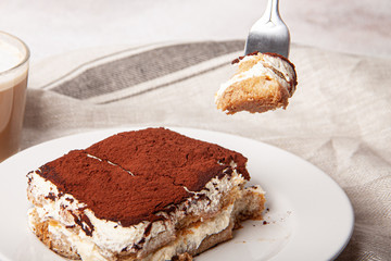 Tasty piece of tiramisu on a fork. Homemade tiramisu closeup.