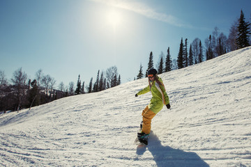 Female snowboarder moving on snow mountain slope