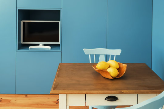 Minimal interior design kitchen in small apartment. Blue walls, yellow lemons on little table
