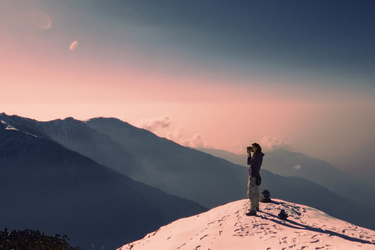 Traveller photographer relaxing on top of snow high mountain and enjoying view of Fishtale mountain, sunrise time, freedom and travel concept