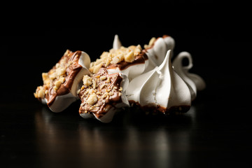 Swiss meringue with chocolate and nuts on a black background
