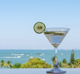 Glass of Lime soda drink with sea view background in summer.