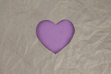 Fototapeta premium Violet felt heart on craft paper. Crumpled paper texture. Valentine's day stock photo for web, print and wallpaper.With empty space for text.