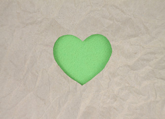 Fototapeta premium Green felt heart on craft paper. Crumpled paper texture. Valentine's day stock photo for web, print and wallpaper.With empty space for text.