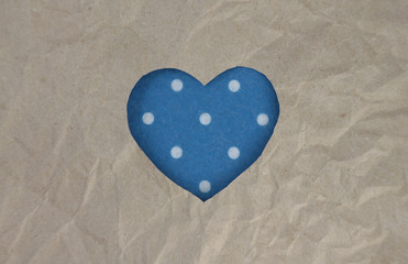 Felt blue heart with polka dot pattern on craft paper. Crumpled paper texture. Valentine's day stock photo for web, print and wallpaper. With empty space for text.