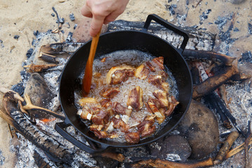 Pieces of lamb are fried in boiling oil in a pan on the fire. As a stage in the preparation of traditional pilaf.