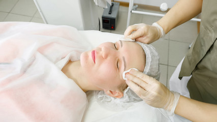 Fototapeta na wymiar beauty salon therapist in white sterile gloves rinses patient face after laser hair removal close view