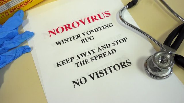 A collection of Norovirus winter vomiting virus notices on a desk. Stopping the spread of infection by allowing no visitors.