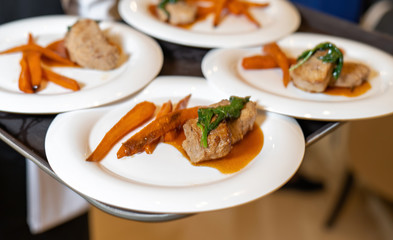 Dishes on a tray, steak with dried carrots.